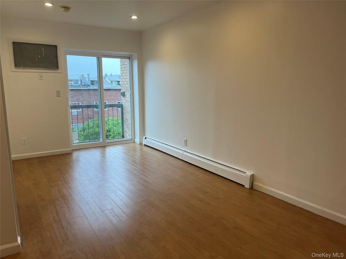 Empty room with a baseboard radiator, wood finished floors, recessed lighting, a smoke detector, and baseboards