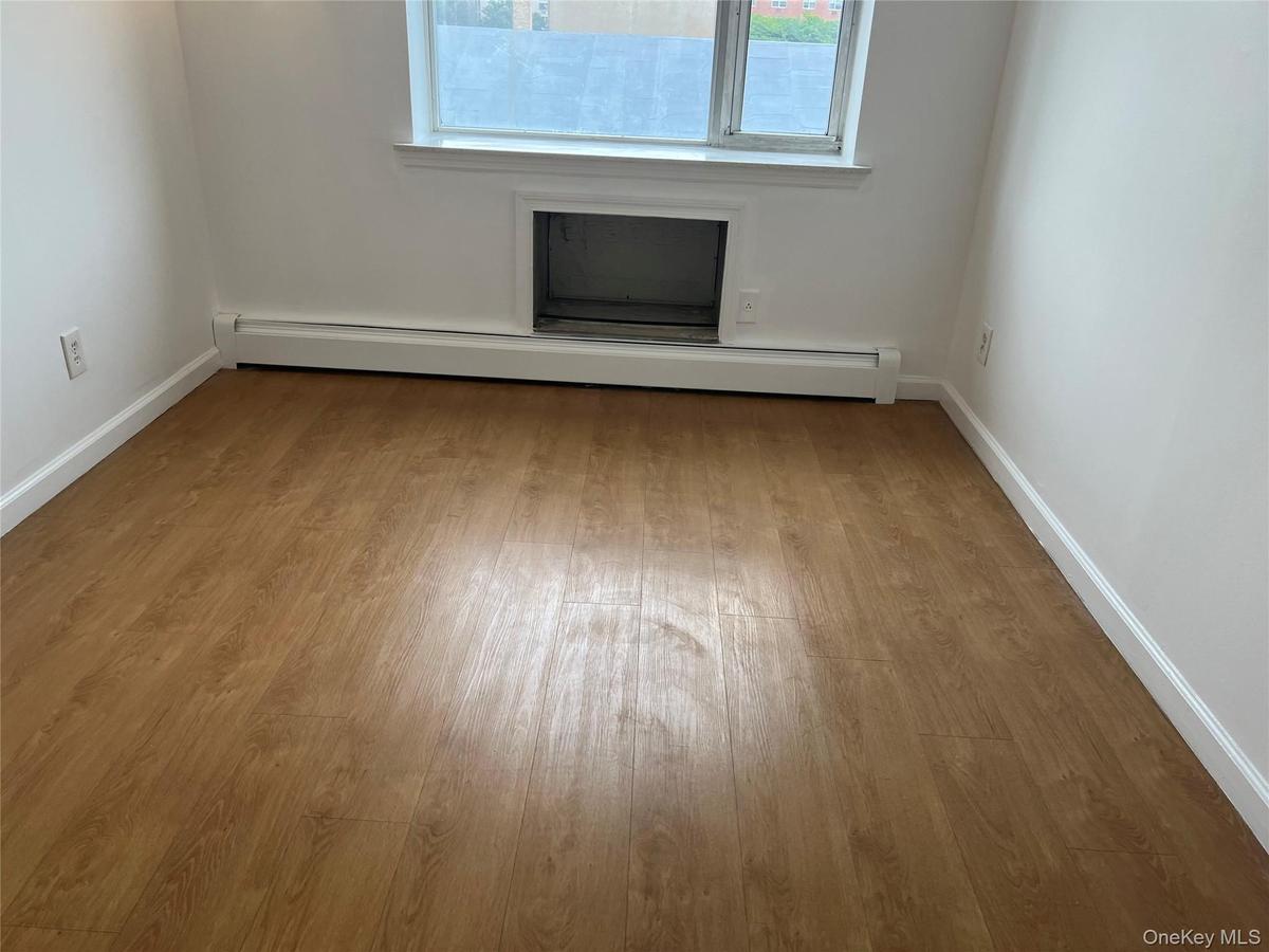 Spare room featuring a baseboard radiator, wood finished floors, and baseboards