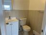 Half bathroom featuring a baseboard heating unit, toilet, vanity, tile walls, and tile patterned flooring