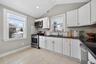 White cabinetry with black granite countertops and subway tile backsplash. Views of the side and backyard.