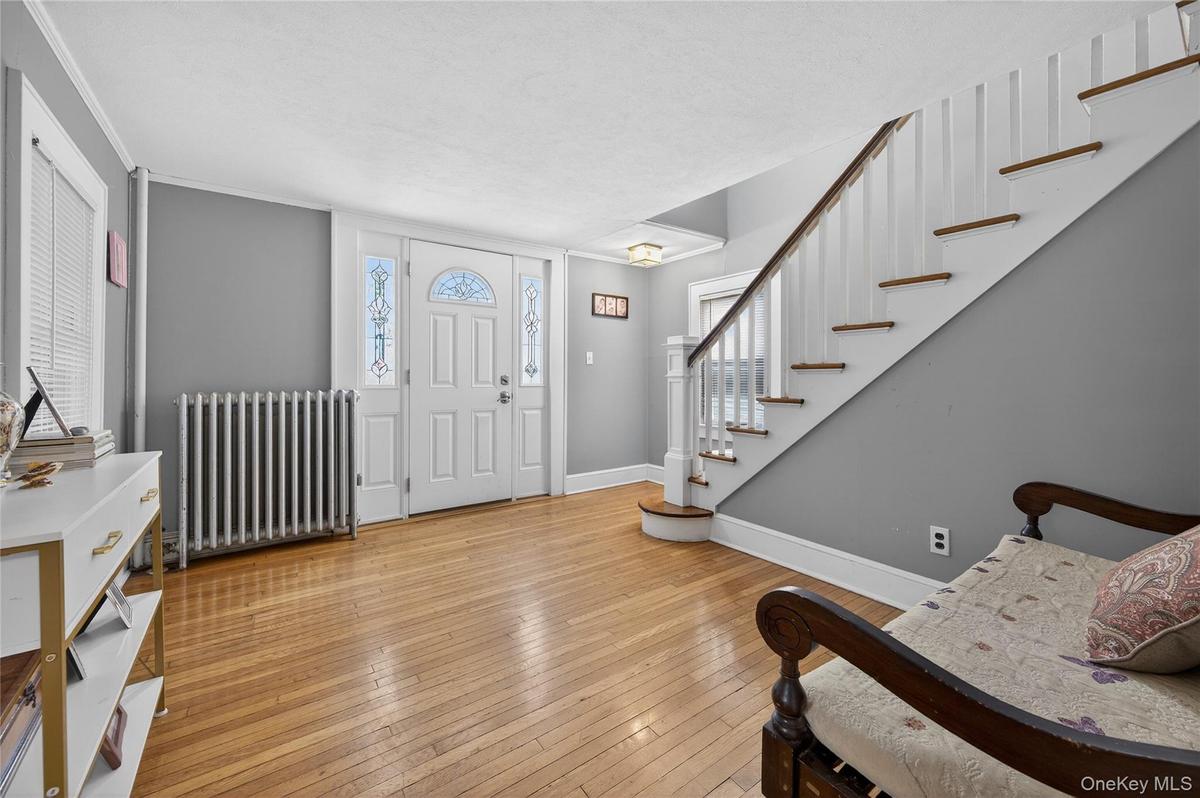 Entry to charming Colonial with deorative  front door side window panels hardwood floors and stairs to the second floor.