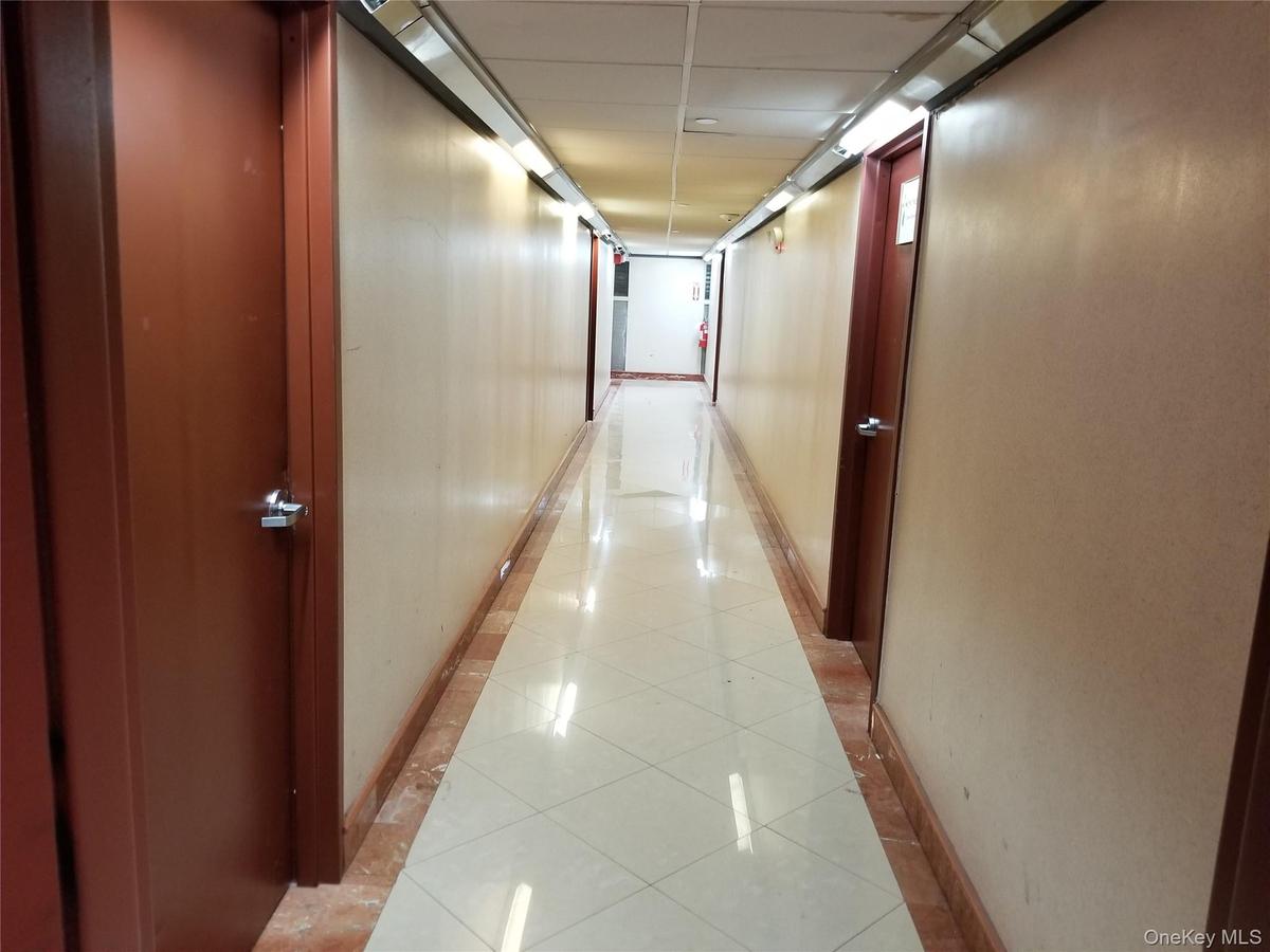 Corridor featuring light tile patterned flooring, a paneled ceiling, and inlaid floor details