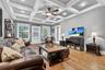 Living area with light wood-style flooring, a ceiling fan, a baseboard heating unit, coffered ceiling, and beamed ceiling