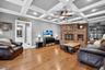 Living room featuring ceiling fan, a fireplace, beamed ceiling, wood finished floors, and coffered ceiling