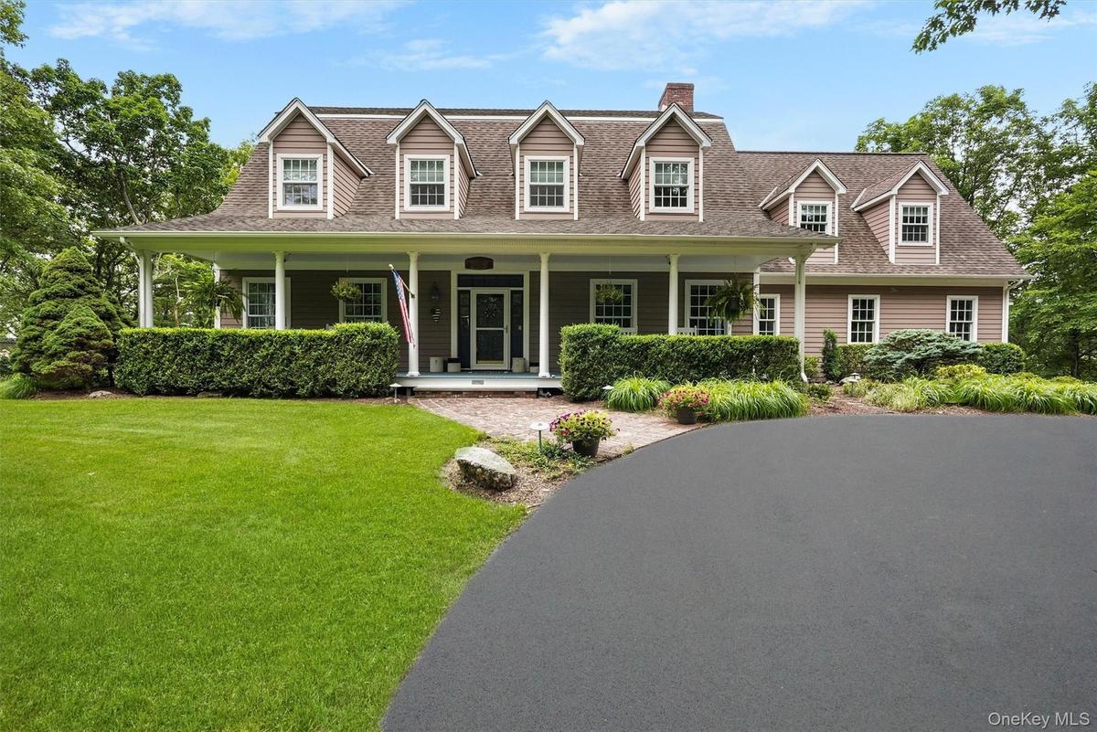 Cape cod house with a front yard, covered porch, a chimney, and a shingled roof