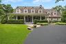 Cape cod house with a front yard, covered porch, a chimney, and a shingled roof