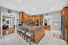 Kitchen featuring appliances with stainless steel finishes, under cabinet range hood, light tile patterned flooring, open shelves, and a peninsula