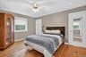 Bedroom featuring baseboard heating, multiple windows, wood finished floors, and ceiling fan