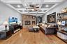 Living area with a ceiling fan, light wood finished floors, a fireplace, coffered ceiling, and beamed ceiling