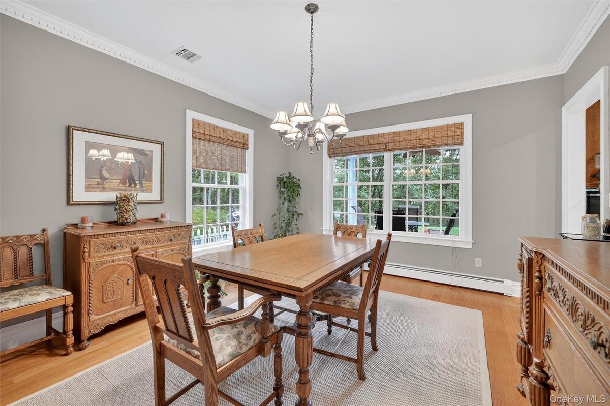 Dining space with a chandelier, ornamental molding, light wood-style flooring, and a baseboard heating unit