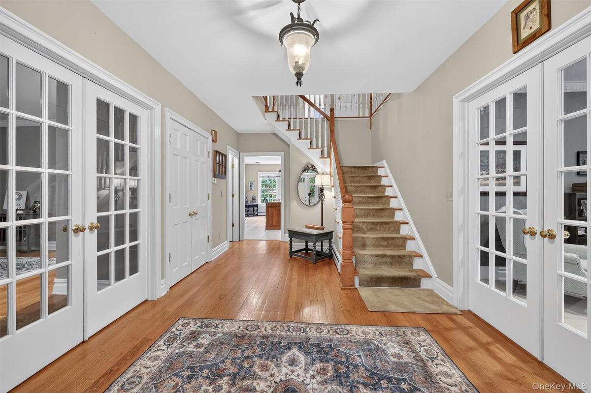 Foyer with french doors, wood finished floors, and stairway