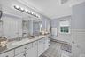 Full bath with a baseboard radiator, tile walls, a wainscoted wall, tile patterned flooring, and double vanity