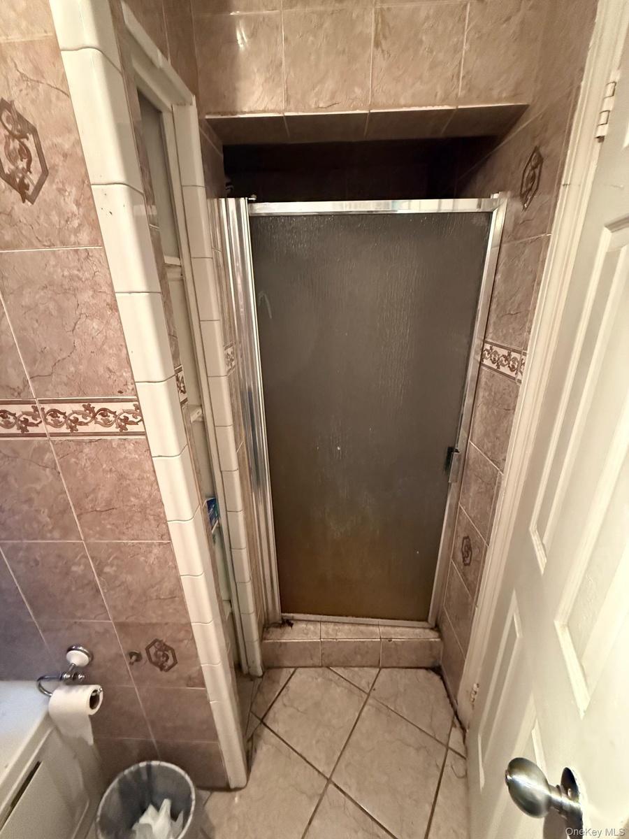 Full bathroom with a shower stall and light tile patterned floors