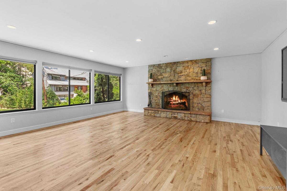 Unfurnished living room featuring baseboards, a fireplace, light wood-style floors, and recessed lighting