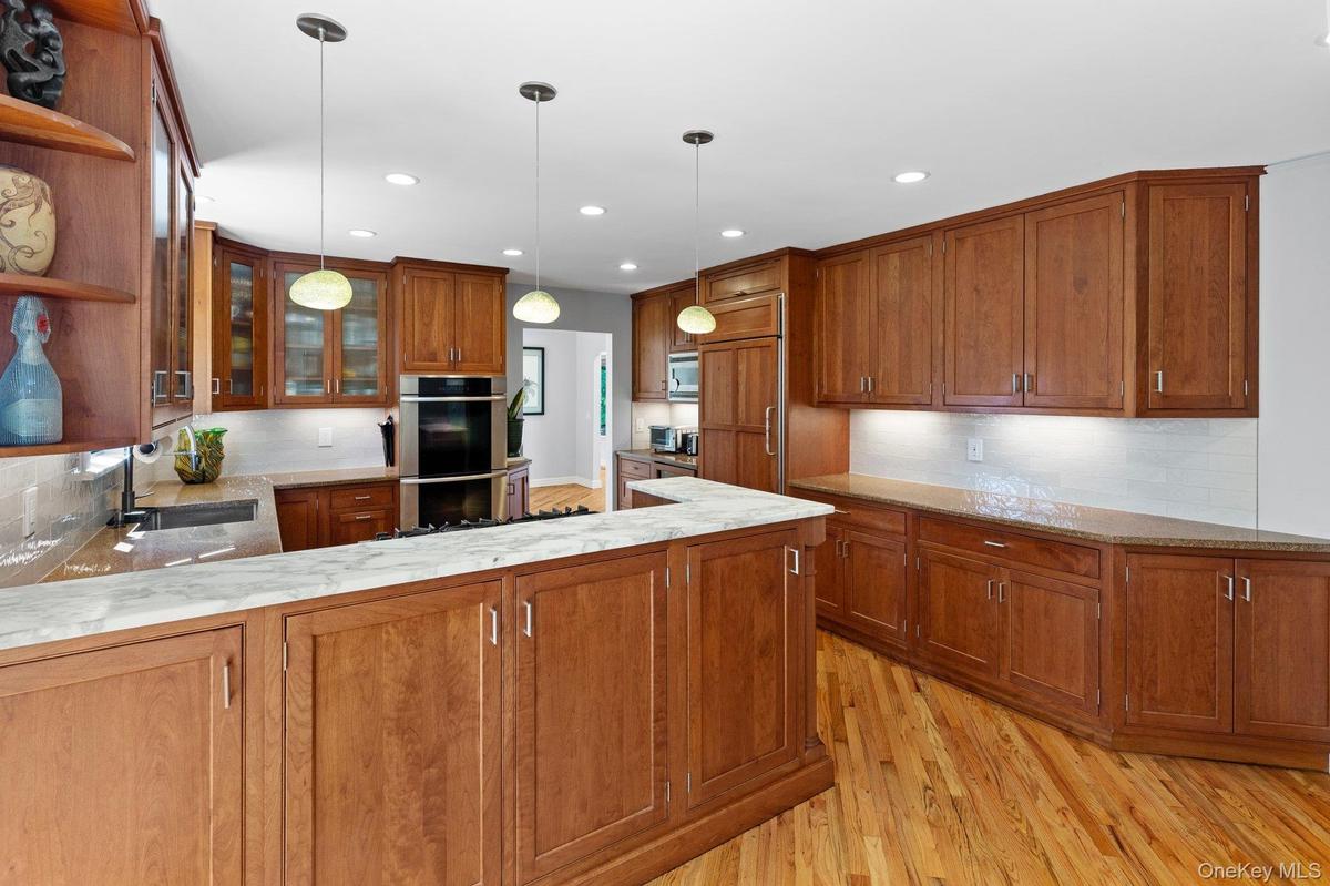 Kitchen featuring open shelves, brown cabinetry, a sink, and stainless steel double oven