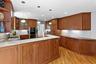 Kitchen featuring open shelves, brown cabinetry, a sink, and stainless steel double oven