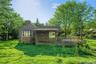 View of side of home with a yard, a wooden deck, and a chimney - Digitally Enhanced