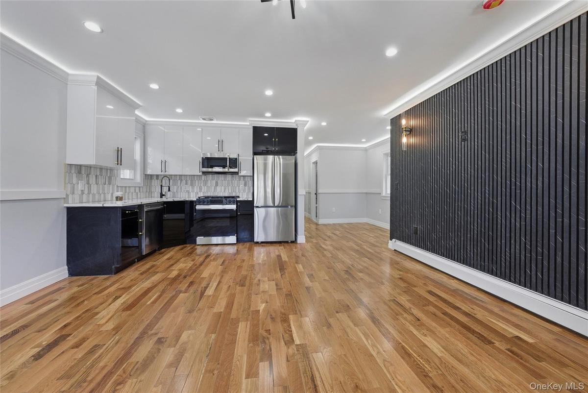 Kitchen with two tone cabinets, light countertops, stainless steel appliances, light wood-style flooring, and recessed lighting