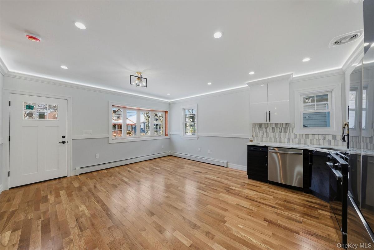 Two tone kitchen featuring dual tone cabinets, dishwasher, light wood-type flooring, ornamental molding, and fridge