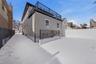 Snow covered back of property with a patio area
