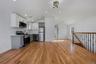 Kitchen with stainless steel appliances, light wood finished floors, two tone color scheme, vaulted ceiling, and open floor plan