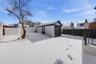 Yard covered in snow featuring a fenced backyard, an outdoor structure, and a detached garage