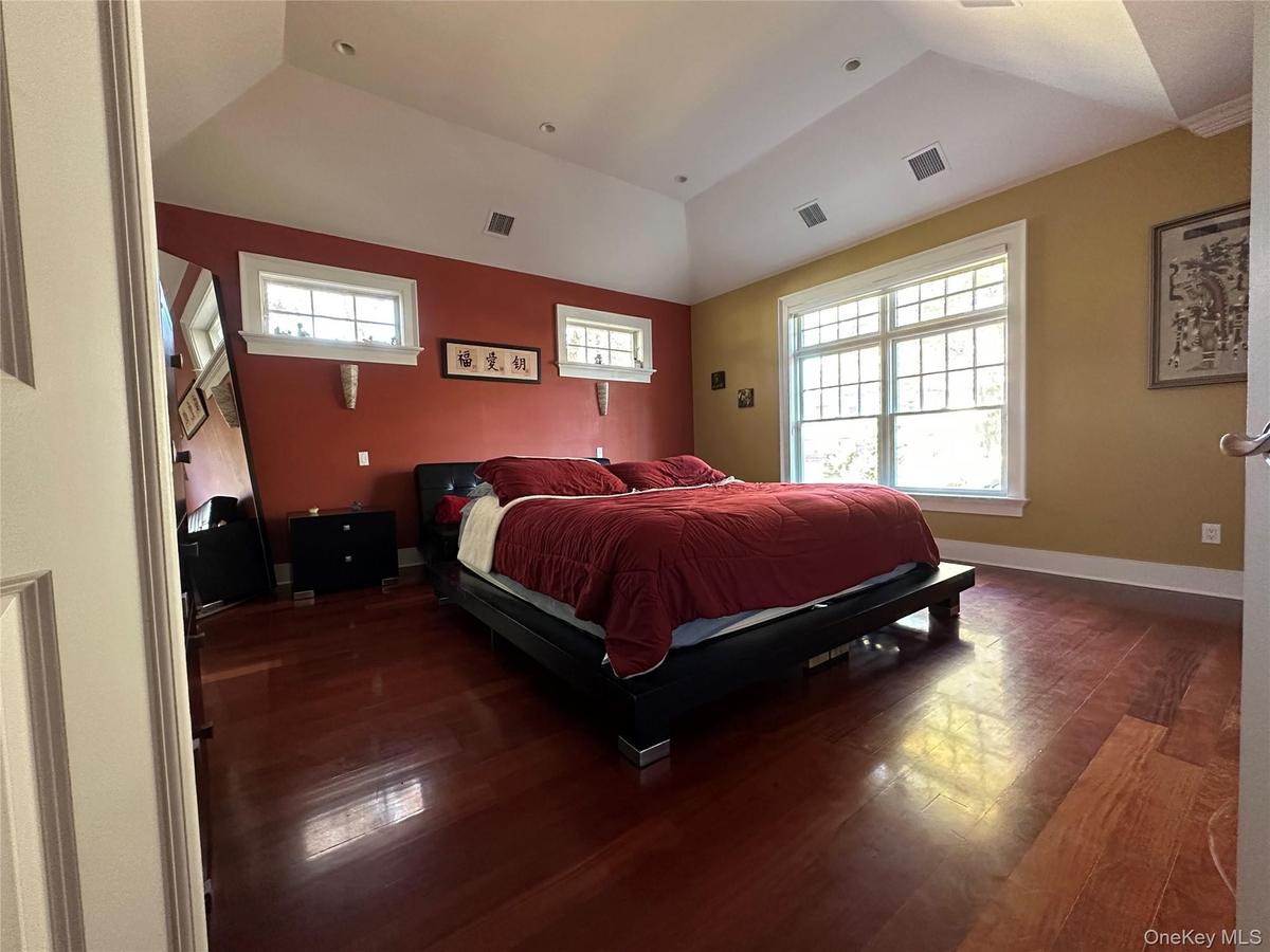 Primary bedroom with a raised ceiling and Brazilian Red Mahogony wide plank wood flooring