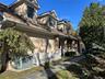 View of side of home featuring stucco facade, covered outside entrance stairs, a chimney, and stone accents
