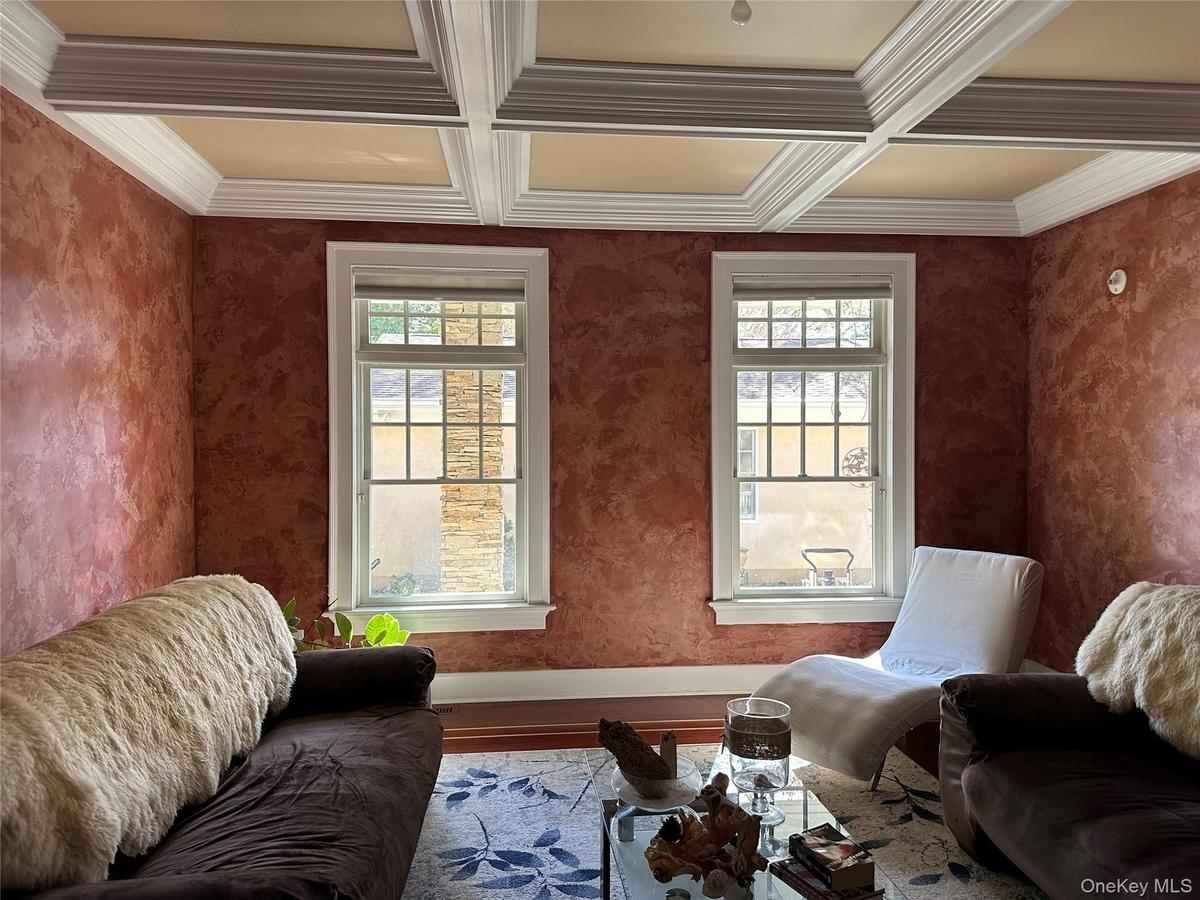 Currently used as a sitting room with healthy amount of natural light, beam ceiling, coffered ceiling, wood finished floors, and crown molding