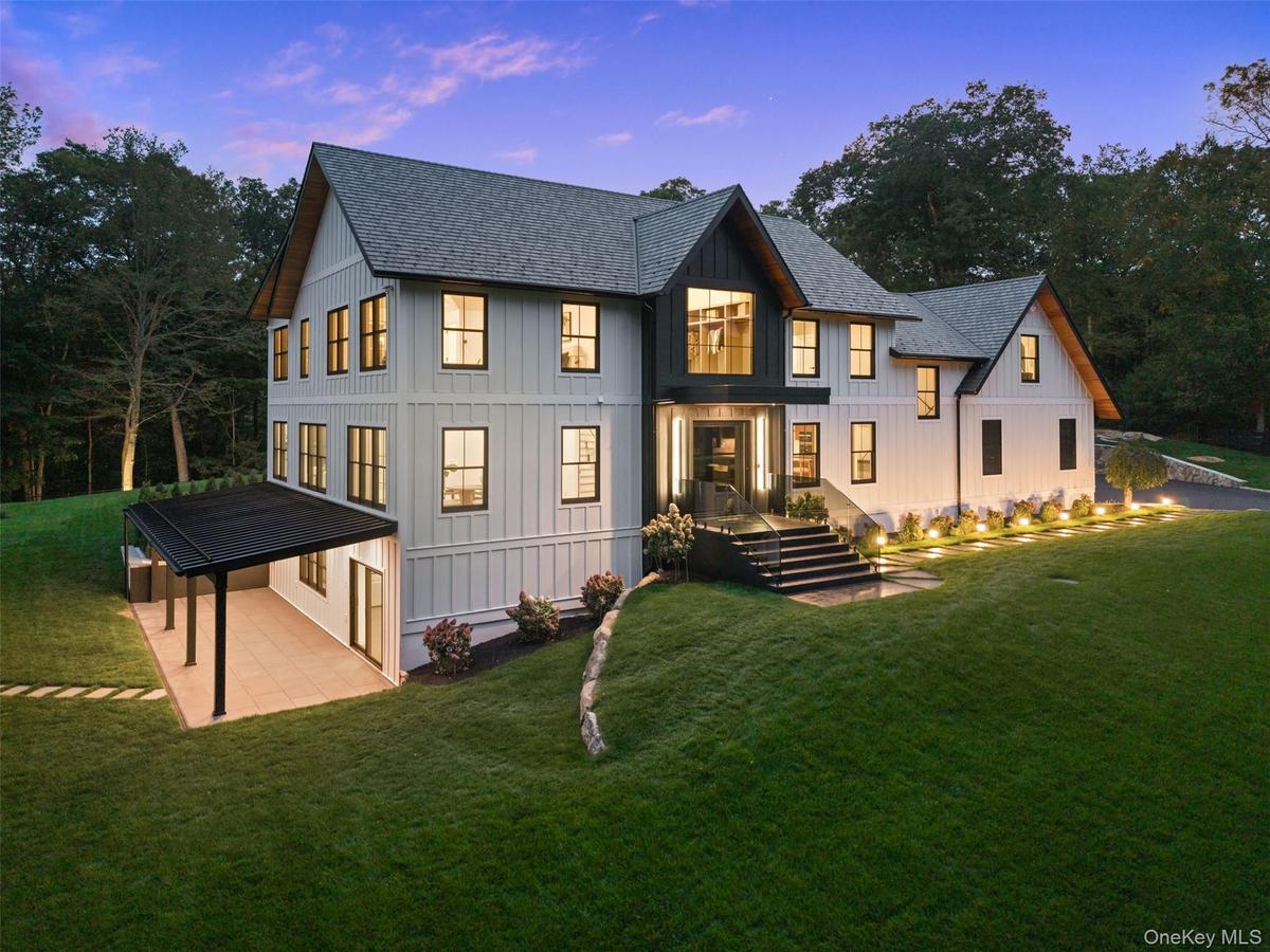 Side view of property at dusk featuring roof with shingles, a yard, and board and batten siding