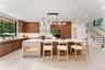 Kitchen featuring brown cabinetry, modern cabinets, decorative backsplash, light stone counters, and decorative light fixtures