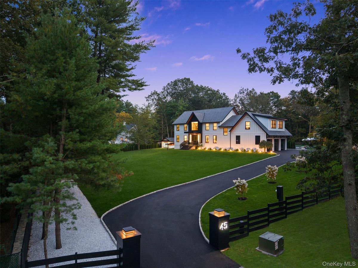 View of driveway of property with a fenced front yard, view of scattered trees, and board and batten siding
