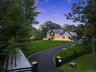 View of driveway of property with a fenced front yard, view of scattered trees, and board and batten siding