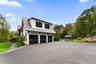Three car garage attached to side of home with basketball hoop in long private driveway.