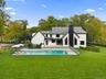 Back of property featuring a patio, a chimney, view of scattered trees, and a metal roof