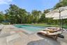 View of swimming pool featuring a patio, a pool with connected hot tub, and view of scattered trees