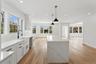 The kitchen features a large center island with a quartz countertop, white cabinetry with black hardware, a farmhouse sink with a black faucet, and ha