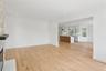 This property features light hardwood floors throughout the living area, leading into an open-concept kitchen with white cabinetry and an island