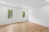 Bright room featuring light-toned hardwood flooring, white walls, and two windows with white frames