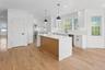 This kitchen features a central island with a light wood base and a white countertop, complemented by white cabinetry and light hardwood flooring