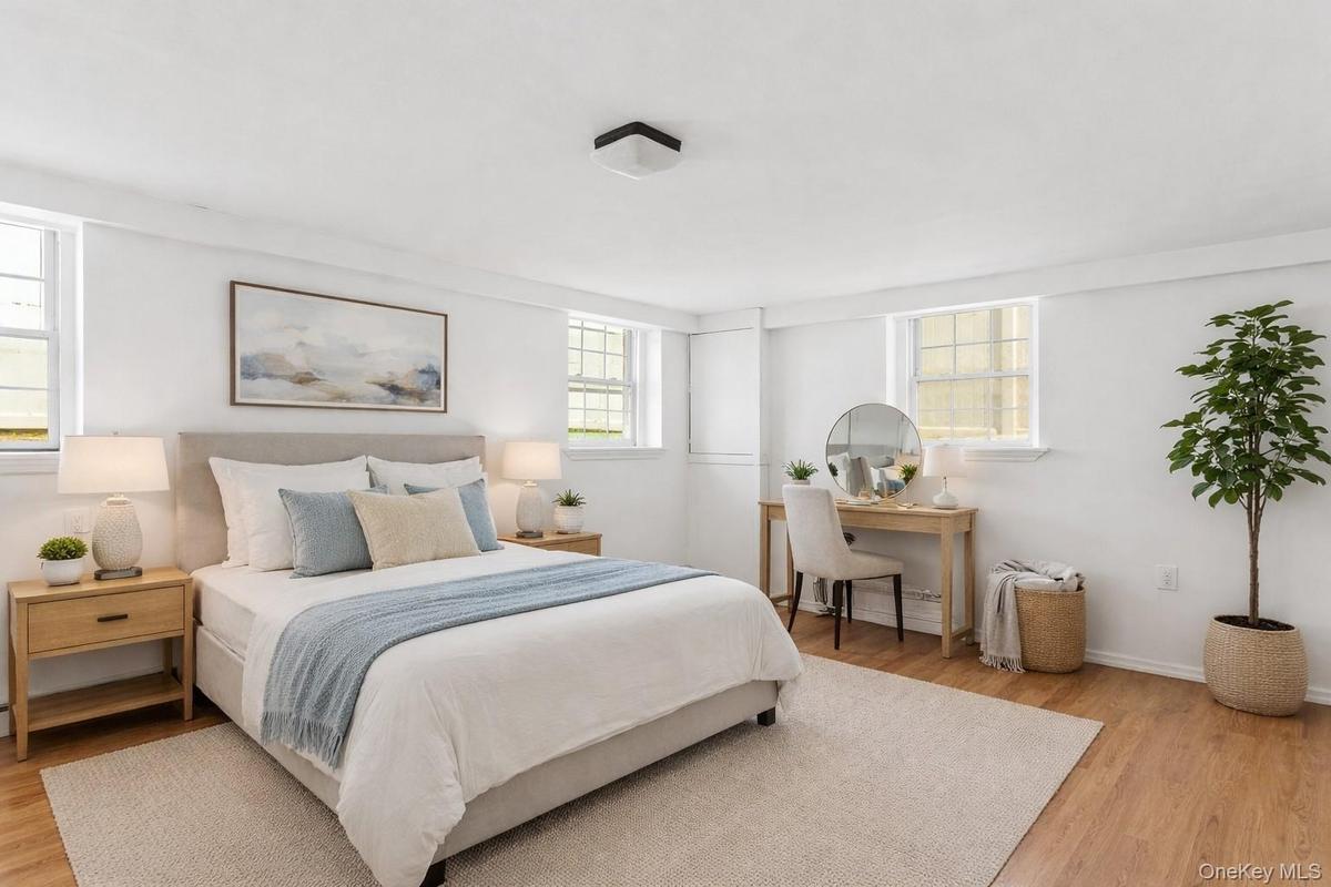 Staged PhotoThis bedroom features light wood flooring and white walls, creating a bright and airy atmosphere