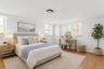 Staged PhotoThis bedroom features light wood flooring and white walls, creating a bright and airy atmosphere
