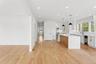 Open concept living area featuring light-toned hardwood floors, recessed lighting, and a kitchen with white cabinetry, a large island with a light woo