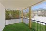 This outdoor area features a covered patio with a ceiling and a faux grass floor, enclosed by black metal railings