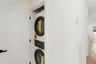 Convenient in-unit laundry featuring a stacked washer and dryer, located behind a white paneled door with a black handle