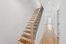 The entry hall features light hardwood flooring, a staircase with light wood treads and a black metal railing, and recessed lighting