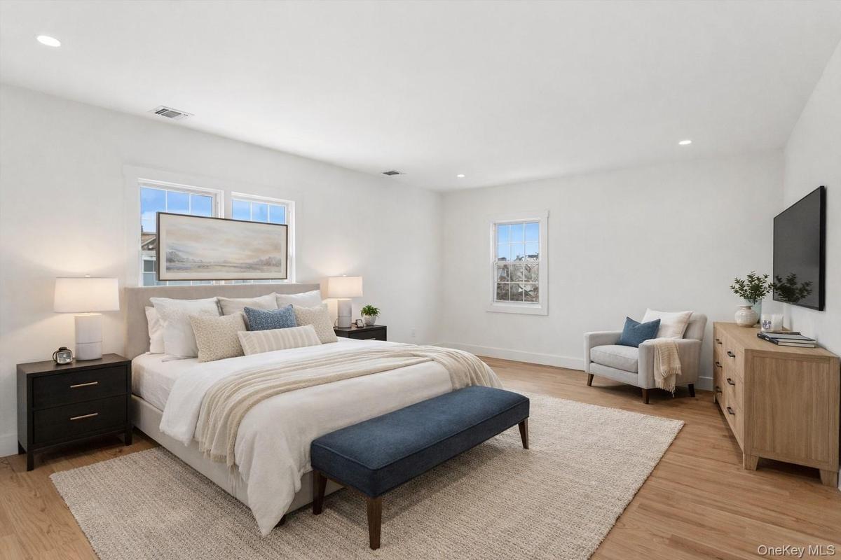 Staged Photo Spacious room featuring hardwood floors, recessed lighting, and ample natural light from multiple windows