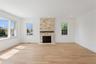 This inviting room features hardwood floors, a stone fireplace with a dark mantel, and recessed lighting
