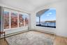 This room features light hardwood flooring, white walls, and an arched window offering a water view