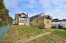 The property features a spacious yard with a mix of lawn and natural ground, a detached garage, and a privacy hedge